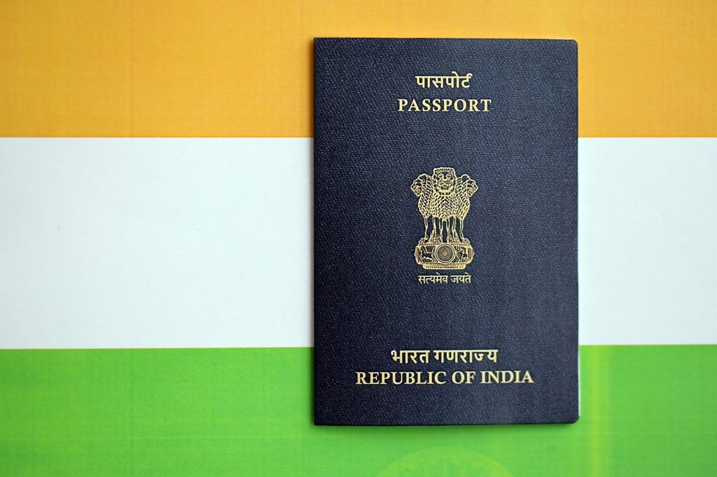 Blue Indian passport on national flag background close up